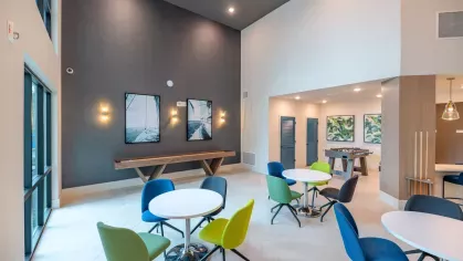 A spacious coworking area at Tropia Wellen Park Apartments featuring comfortable seating, private workstations, and large windows for natural light.