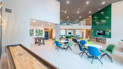 A spacious coworking area at Tropia Wellen Park Apartments featuring comfortable seating, private workstations, and large windows for natural light.