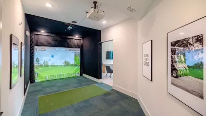 A high-tech golf simulator room at Tropia Wellen Park Apartments, providing an immersive virtual golfing experience for residents.
