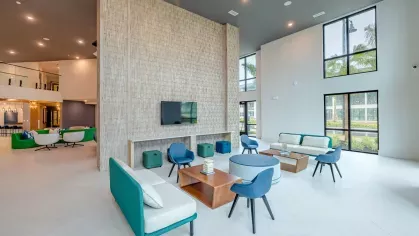 A spacious coworking area at Tropia Wellen Park Apartments featuring comfortable seating, private workstations, and large windows for natural light.