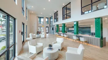 A spacious coworking area at Tropia Wellen Park Apartments featuring comfortable seating, private workstations, and large windows for natural light.