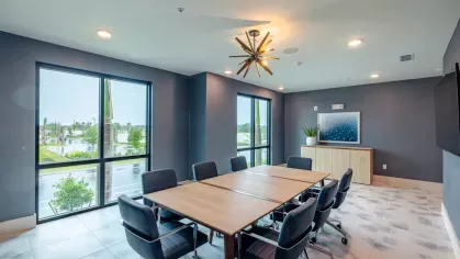 A contemporary conference room with a large meeting table, ergonomic chairs, and natural light from large windows.