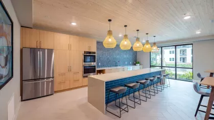 A fully equipped community kitchen with a long island counter, pendant lighting, and sleek cabinetry.