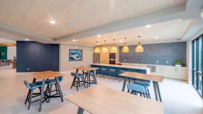 A fully equipped community kitchen with a long island counter, pendant lighting, and sleek cabinetry.