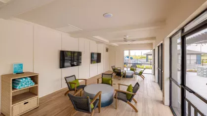 An indoor-outdoor community space with cozy seating, large televisions, and expansive views of the pool area.