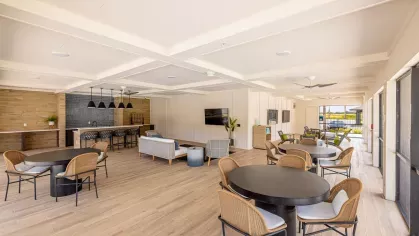 An indoor-outdoor community space with cozy seating, large televisions, and expansive views of the pool area.