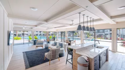 An indoor-outdoor community space with cozy seating, large televisions, and expansive views of the pool area.