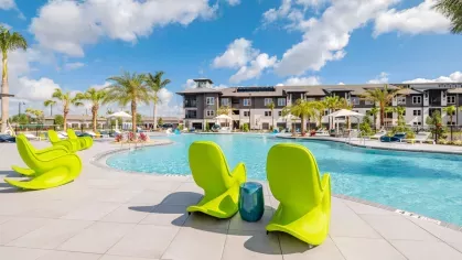 "Spacious resort-style pool with vibrant green lounge chairs at Tropia Wellen Park Apartments."