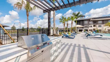 "Outdoor grilling station with a shaded pergola and seating area at Tropia Wellen Park Apartments."