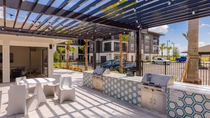 "Outdoor grilling station with a shaded pergola and seating area at Tropia Wellen Park Apartments."
