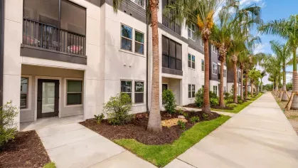 "Screened balconies and walkways surrounded by lush greenery at Tropia Wellen Park Apartments."