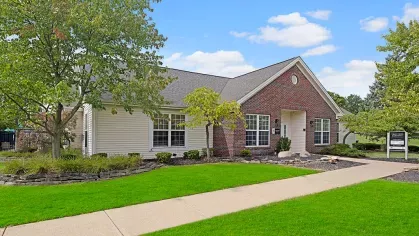 A charming brick and siding clubhouse surrounded by landscaped greenery, offering a welcoming entrance for residents.