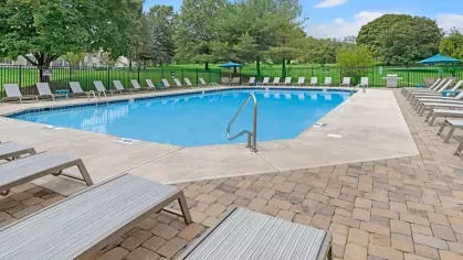 A sparkling outdoor pool with ample lounge chairs and umbrellas, providing a relaxing spot for residents to enjoy the sun.