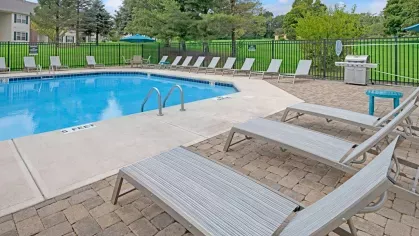 A sparkling outdoor pool with ample lounge chairs and umbrellas, providing a relaxing spot for residents to enjoy the sun.