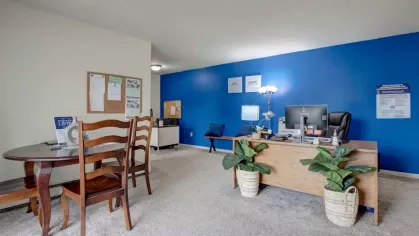 Bright and welcoming office space with a bold blue accent wall and stylish furniture at Washington Gardens Apartments in Washington, NJ.