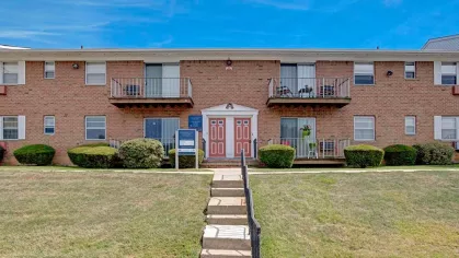 Well-maintained pathways leading to the entrances of Washington Gardens Apartments, with neatly trimmed bushes and balconies, exemplifying suburban comfort.