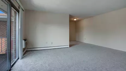 Open living space with large windows, modern carpeting, and access to a private balcony at Washington Gardens Apartments in Washington, NJ.