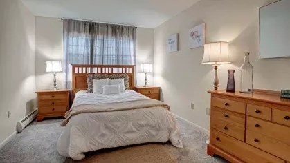 Cozy and stylishly decorated bedroom with soft lighting, elegant furnishings, and plush carpeting at Washington Gardens Apartments in Washington, NJ.