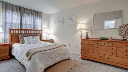 Beautifully arranged bedroom with warm wooden furniture, large windows, and contemporary decor at Washington Gardens Apartments in Washington, NJ.