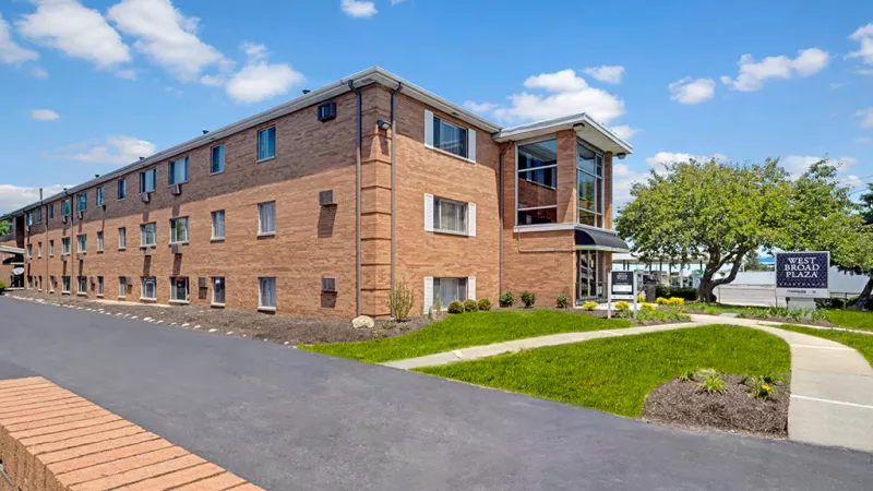 Exterior view of West Broad Plaza Apartments showcasing a well-maintained property with brick facade and green space.