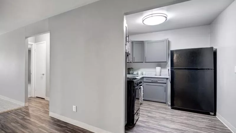 Open kitchen design with gray cabinetry, black appliances, and hardwood-style flooring.