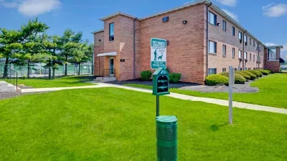 Pet-friendly outdoor area with a waste station and walking paths, surrounded by lush green lawns.