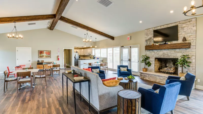 "Modern clubhouse at Worthington Meadows Apartments featuring cozy seating, a fireplace, and natural light from large windows."