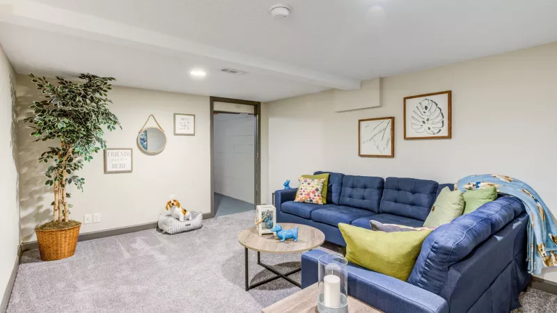 Comfortable living room with a navy sectional couch, decorative pillows, and stylish decor at Worthington Meadows Apartments.