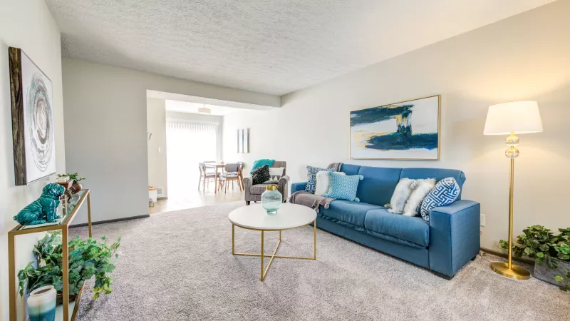 Comfortable living room with a navy sectional couch, decorative pillows, and stylish decor at Worthington Meadows Apartments.