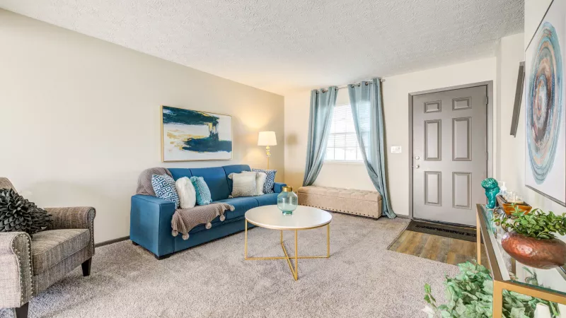 Comfortable living room with a navy sectional couch, decorative pillows, and stylish decor at Worthington Meadows Apartments.