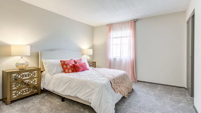 Elegant bedroom featuring a queen-sized bed, stylish bedding, and soft lighting in Worthington Meadows Apartments.