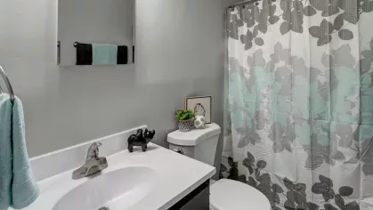 A modern bathroom with a clean white vanity, decorative shower curtain, and contemporary fixtures at Yearling Plaza Apartments in Columbus, OH.