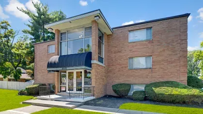 Exterior view of Yearling Plaza Apartments in Columbus, OH, showcasing a well-maintained brick building surrounded by manicured landscaping and a welcoming entrance.