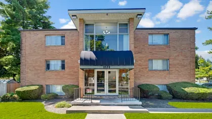Exterior view of Yearling Plaza Apartments in Columbus, OH, showcasing a well-maintained brick building surrounded by manicured landscaping and a welcoming entrance.