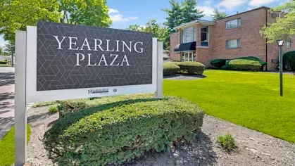 Close-up of the Yearling Plaza sign in Columbus, OH, highlighting the modern branding and lush greenery surrounding the property.