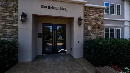  Entrance to The Grove Somerset Apartments, featuring a stone and stucco facade with double glass doors and landscaped greenery for a welcoming entry.