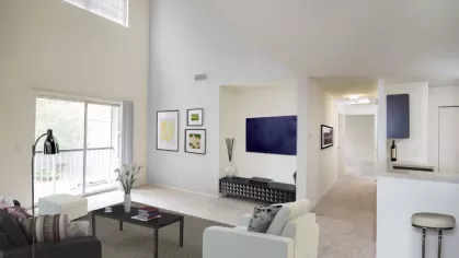 A contemporary living room with an open floor plan, plush carpeting, and large windows that open to a private balcony, allowing for abundant natural light.