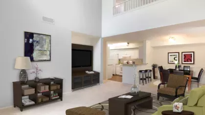 A beautifully designed apartment living area with a neutral color scheme, plush carpeting, and a stylish dining setup.