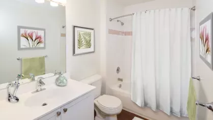 A well-lit bathroom with a modern white vanity, large mirror, and a sleek bathtub for relaxation.
