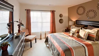 A spacious bedroom with a large bed, stylish decor, and warm-toned accents, creating a cozy and inviting atmosphere.