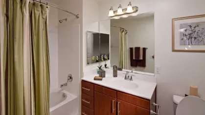 A well-lit bathroom with a modern white vanity, large mirror, and a sleek bathtub for relaxation.