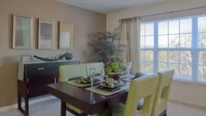 Elegant dining area with a dark wood table, lime-green chairs, and a large window offering scenic views, perfect for entertaining.