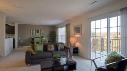 Spacious living area with contemporary furnishings, a large sectional sofa, and floor-to-ceiling sliding glass doors leading to a private balcony with scenic views.