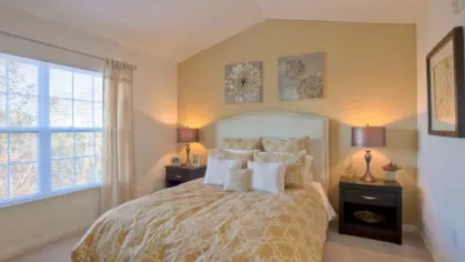Elegant bedroom with a vaulted ceiling, soft lighting, and warm-toned decor, offering a cozy and inviting retreat at Vista At Town Green Luxury Apartments.