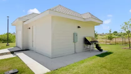 A small standalone building with white siding and a neatly maintained lawn.