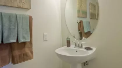 Stylish half-bathroom with a pedestal sink, round mirror, and soft ambient lighting, creating a refined and functional space.