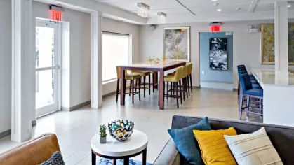 A modern resident lounge at Vista At Town Green Luxury Apartments, featuring a high-top table, bar seating, and contemporary decor for socializing and relaxation.