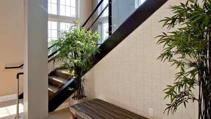 A bright and inviting staircase at Vista At Town Green Luxury Apartments, with modern glass railings, natural light, and lush greenery enhancing the space.