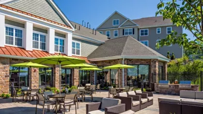 Spacious outdoor patio with shaded dining tables and comfortable lounge seating, perfect for entertaining or relaxing in a beautifully landscaped environment.