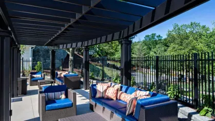 Shaded pergola with cozy seating, offering a tranquil retreat by the poolside at Vista At Town Green Luxury Apartments.